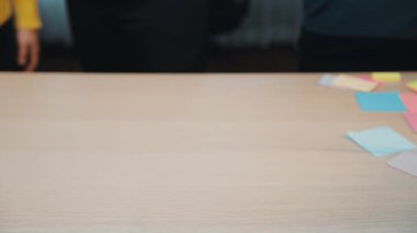 Canlı bir takım işbirliği sahnesi renkli yapışkan notlarla kaplı ahşap bir masa sergiliyor. Profesyoneller beyin fırtınası ve fikir paylaşımı yapar, yaratıcılığı teşvik ederler. SACTR