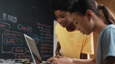 Tatlı kız dizüstü bilgisayar kodlaması yazarken ya da mühendislik sistemini programlarken mutlu Afrikalı çocuk ekranı işaret ediyor. BTMM teknoloji sınıfında dizüstü bilgisayar tutarken öğretmen eğitim programı. Öğretim