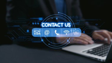 Bu stok görüntüsü modern bir kontak bizimle iletişim kuruyor bir dizüstü bilgisayarın üzerini örtüyor, karanlık bir kurumsal ortamda ellerini gösteriyor, iş iletişimi araçlarını vurguluyor. Dörtgen