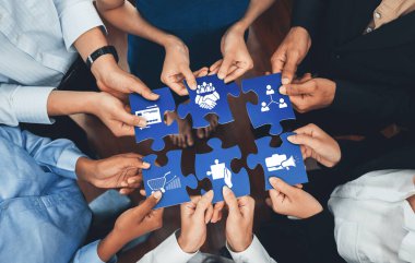 Çeşitli el grupları bir araya gelerek, profesyonel bir ortamda işbirliği, iş ortaklığı ve stratejik planlamayı sembolize eden yapboz parçaları yerleştiriyorlar. Dostluk