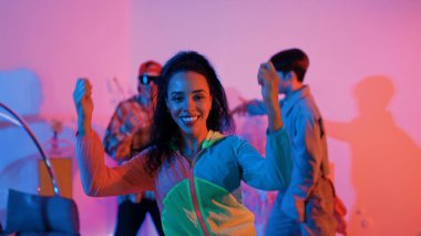 Çekici mutlu dansçı kameraya bakarken zeki kadın neon ışıkla kafiyeli hareket ediyor. Profesyonel İspanyol şarkıcı çeşitli arkadaşlarıyla renkli kıyafetler giyerken break dans yapıyor. Mutluluk.