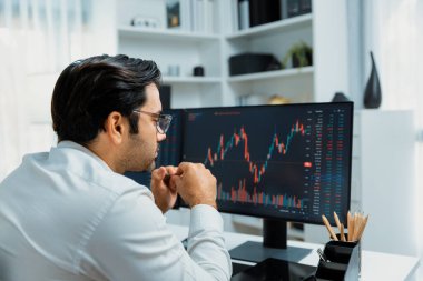 Akıllı tüccar işadamı, modern merkez ofisindeki araştırma pazarında en yüksek kârlı finansal teknolojiye yatırım yaparak bilgisayar üzerinde iki dinamik borsa yatırım ekranını analiz ediyor. Tahmin et..