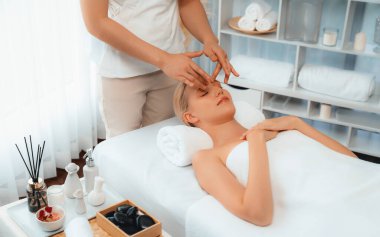 Kafkasyalı kadın stres önleyici kafa masajından ve lüks tatil beldesi ya da otel spa salonundaki modern ışık ortamında yüz güzelliği eğlencelerini şımartmaktan hoşlanıyor. Sessiz.