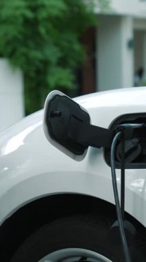 Bir kadın evinde elektrikli araç şarj aletinin fişini çekiyor. İlerici bir yaşam tarzında elektrikli araçların kullanımı, temiz ve sağlıklı bir çevreye katkıda bulunur..