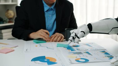 Bir iş toplantısı sırasında insan zekası ve robot yardımının eşsiz bir karışımı. Zarif bir ofis ortamında veri analizine ve grafiklere odaklanıyor. Noogenesis