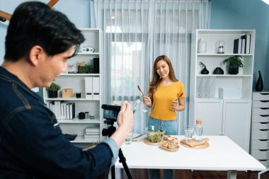 Asyalı güzel kadın yemek uzmanı blog yazarı akıllı kameramanın sosyal medya kavramında canlı yayında kaydettiği canlı yayında salatanın nasıl kolay pişirileceğini öğretiyor. İnfobahn.