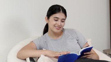 Kanepede oturan bir kadın ders kitabı okuyarak sosyal ve mesleki teknoloji bilgisini artırır ya da akıllı bir anne olmak için çocuk yetiştirir. Hayat boyu öğrenme konsepti. Uyumsuzluk.