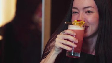 Paloma 'da fermuarlı kokteyl içen gülümseyen güzel bir kadın vişneli limon özel menüsüyle süslenmiş hoş bir içecek, lüks bir barda arkadaşla sıcak bir gece kulübü partisinde ferahlatıcı bir içecek. Vinosity.