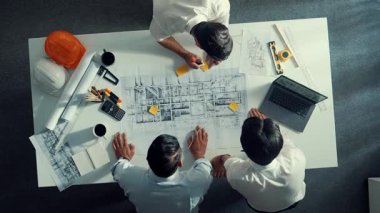 Mühendis ekibiyle tasarım planlarken iç mimar yazımının yukarıdan aşağı görüntüsü yapışkan notta. Çeşitli mimarlar ve usta yöneticilerden oluşan bir grup bina inşaatı arıyor. Hizalama.