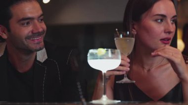 Lezzetli tadını çıkarmak için martini kokteyli içen bir kadın, çiftle canlı sohbetler ederken, margaritanın tadını çıkarırken, gece kulübü barında özel bir an yaratıyor. Vinosity.