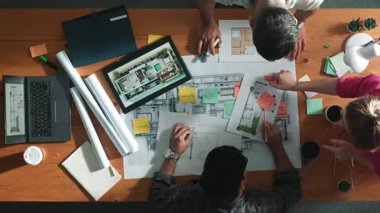 İnşaat mühendisi ekibi toplantıda beklerken yapışkan nota bakıyor. Tasarımcının çalışmasına ve notlara bakmasına ilişkin en üst görünüm, meslektaşı açıklama yaparken ve birlikte çalışırken planda yer alıyor. Sempozyum.