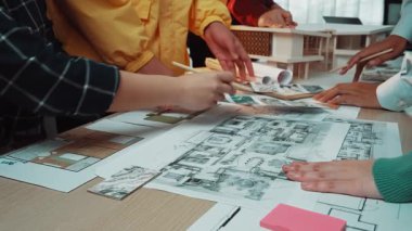 İşbirlikçi bir ofis ortamını gösteren dinamik bir sahne, birden fazla bireyin proje tasarımıyla uğraşması için planlar ve yaratıcı araçlar kullanması, takım çalışmasını ve yenilikleri teşvik etmesi. SACTR