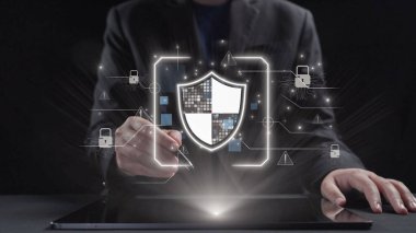 Takım elbiseli profesyonel bir adam, koruma sembolleri ve teknolojik grafikler ağının ortasındaki bir kalkan ikonu ile dijital güvenliği resmeden bir tabletle etkileşime girer. Dörtgen