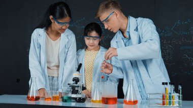 Zeki kız deney yapmak için heyecanlanan çeşitli öğrenciler iken beher kabına renkli solüsyon döker. Profesyonel bilim adamı kimyasal teoriyle kara tahtada deney yapmaya hazırlanıyor. Öğretim.