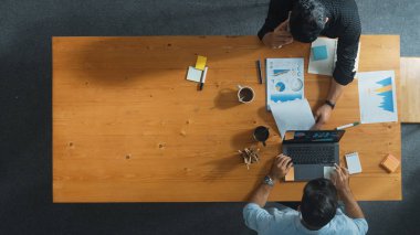 Bilgi analiz belgeleriyle toplantı masasında otururken yatırımcılarla finansal grafik hakkında konuşan yetenekli proje yöneticisinin üst görüşü. Çeşitli takımlar tartışır ve beyin fırtınası yapar. Cemaat.