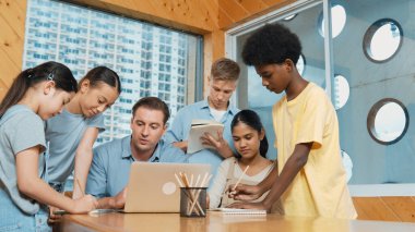 Akıllı robotlar sınıfta dizüstü bilgisayar ekranını işaret ederken, beyaz bir öğretmen yorum yapıyor ya da öğrencilere tavsiye veriyor. Öğretmen bilgisayar kullanırken çeşitli öğrencilerin ders verirken not alması. Öğretim.