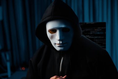 Tanımlanamayan beyaz suçlu maskesi profil pozuna bakıyor, geceleri bilgisayar başında sunucu sürücüsü sistemi olan mavi neon aydınlatma odasında virüs şifrelemesi kuruyor. Tahmin et..