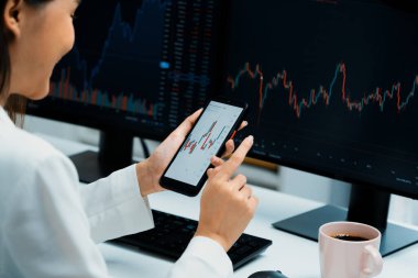 Modern ofisteki bilgisayar ekranlarıyla karşılaştırıldığında borsa grafiği üzerinden akıllı telefon kullanan bir iş kadınında kesilmiş görüntü. Zenginlik güvenliğine yüksek kar yatırımı kavramı. Taktik.