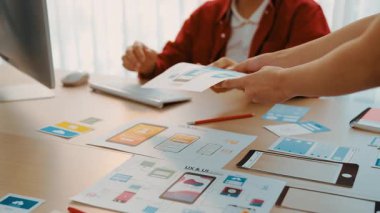 Mobil uygulama için kullanıcı arayüzü prototipini ofis çalışma alanındaki akıllı yöneticiye sunan mükemmel bir şirket çalışanı. UX UI tasarımcısı kağıt üzerinde simge tasarımının işlevini açıklıyor. Sinerjik