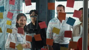 Cam duvarda yaratıcı fikirleri paylaşmak için renkli yapışkan notlar kullanarak pazarlama fikrini değerlendiren mutlu profesyonel iş adamları. Bir grup farklı iş adamları strateji hakkında tartışıyorlar. Yönlendirici.