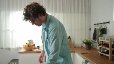 Mutlu baba yemek pişirirken müziğe geçiyor ve modern mutfakta öğle yemeği hazırlıyor. Aktif baba, sebze ve mutfak gereçleri ile çevrili sağlıklı yemek ya da salata yaparken şarkıyla dans ediyor. Pedagoji.