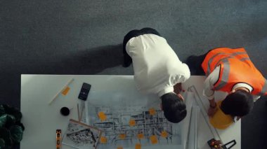 Akıllı mimar ve yetenekli inşaat mühendisi ekibinin, bina inşaatı için birlikte çalışırken proje, ekipman ve güvenlik kaskıyla toplantı masasında durmasının en iyi görüntüsü. Hizalama.