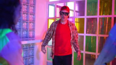 Kafkas dansçısı dans ederken çeşitli arkadaşları gece kulübünde neon ışıkta ayak seslerine bakıyor. Çoklu etnik kökenli hipsterin serbest stil müziğe geçişi ve mutlu bir adamın kameraya bakışıyla. Mutluluk.