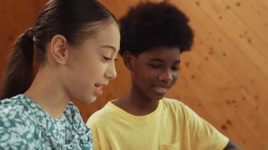 Afrika 'lı bir erkek ve beyaz bir kızın günlük giysiler içinde BTMM teknoloji sınıfında dizüstü bilgisayar ve elektronik ekipmanlarla kod yazma ya da programlama sisteminde birlikte çalıştıklarını gösteren site görüntüsü. Öğretim