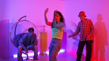 İspanyol hipster renkli kıyafetler giyer ve serbest stil müziğe el sallar. Profesyonel break dansçı neon ışıklarıyla ve modern stüdyo arkadaşlarıyla coşkuyla dans ediyor. Mutluluk.