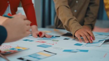 Dinamik bir beyin fırtınası, yenilikçi tasarım fikirleri üzerinde işbirliği yapan çeşitli profesyonelleri yakalıyor. Masada renkli çizimler ve stratejik planlar var. SACTR