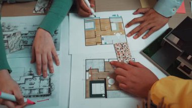 Mimari planlama üzerine dinamik bir işbirliği içinde olan iki birey, tasarım sürecinin yaratıcılığını gösteren çizimler ve planlarla çevrelenmiştir. SACTR