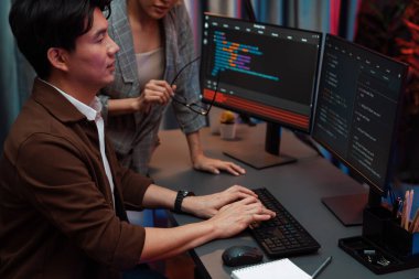 Bilgi teknolojisi geliştiricileri modern ofisteki neon ışık odasında verileri çevrimiçi olarak çalıştıran akıllı web sitesi geliştirme kodlayıcı sistemine işaret ediyorlar. İnfobahn.