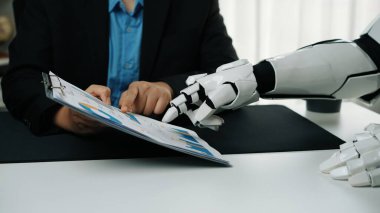 Bir robotik el iş toplantısı sırasında insanlarla etkileşime girer, teknolojinin iş yeri dinamikleri ve işbirlikçi stratejilere entegrasyonunu gösterir. Noogenesis