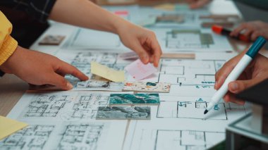 Eller, proje planlama ve tasarımda işbirliği ve yaratıcılığı gösteren canlı bir çalışma alanında notlara ve çizimlere uzanır. Çeşitli malzemeler takım çalışmalarını ön plana çıkarıyor. SACTR