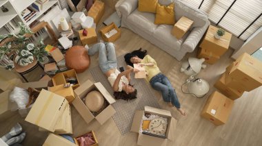 Oturma odasının zemininde karton kutuyla çevrili yatan lezbiyen çiftin hikayelerini kitapla paylaşırken en tepeden aşağıya bakışı. Mutlu aşıklar birlikte vakit geçirir ve birlikte gülerler. Myrmidon.