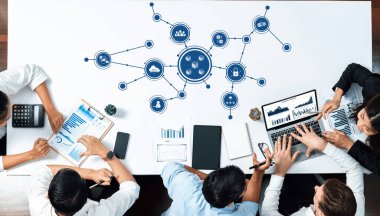 Stratejik bir iş toplantısında yer alan çeşitli profesyonellerden oluşan bir grup, işbirliğini ve karar vermeyi geliştirmek için dijital araçlardan ve veri görselleştirmesinden yararlanıyor. Dostluk