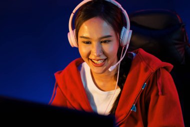 Portre sunucusu güzel Asyalı kız flamasının çevrimiçi oyun oynaması kulaklık takması pastel renkli konuşmalar izleyici medyası ile çevrimiçi. Esport yetenekli takım oyuncuları neon mavi odada. Taktik.