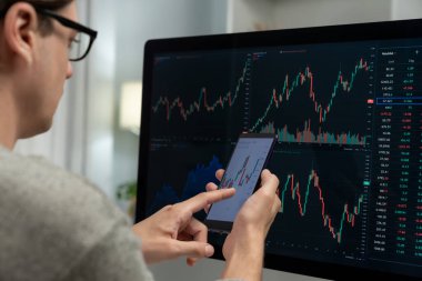 Akıllı borsa yatırımcıları ekranda akıllı telefon ile piyasa borsasını işaret ederek dizüstü bilgisayarın yanı sıra en yüksek dinamik yatırım oranını göstererek, modern işyerindeki veri planlamasına odaklanıyorlar. Bireysel.