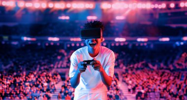 Yetişkinlerin elinde joystickle VR gözlükleri varken stadyumda arka planda bulanık oyunlar oynamaktan zevk alıyorlar. Afrikalı adam kontrol etmeyi ve artırılmış gerçeklik teknolojisini kullanmayı seviyor. Yaratıcılık.