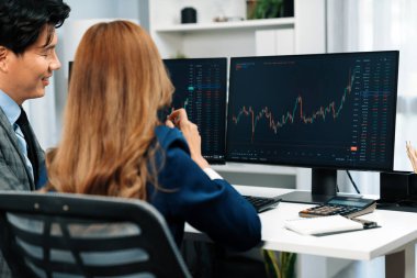 Gülümseyen iş kadını cep telefonunda dinamik borsayı erkek ortağa gösteriyor. Kâr değeri çevrimiçi para birimi çevrimiçi web sitesi programını analiz ediyor. Ofisin arka tarafındaki bilgisayarda karşılaştırıyor. İnfobahn.