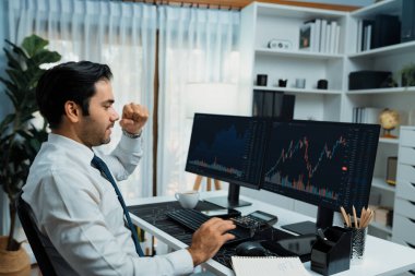 İki borsa yatırım ekranı olan tüccar işadamında başarılı olmak, çalışma masasında yüksek kar elde etmek için yumruğunu kaldırmak, ofisteki borsada dinamik teknoloji grafiği. Tahmin et..