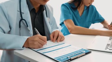 Hastane masasında birlikte çalışan ve tıbbi tedavi planlayan çeşitli profesyonel sağlık görevlileri. Takım çalışması başarılı hastalıklara ve hastalıklara yol açar. Ağır çekim. Katı.