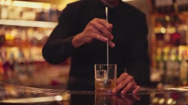 Zeki Asyalı barmen bardakta karıştırılmış alkol şurubunu buzla karıştırıyor. Çünkü kayanın üzerinde kamera var. Gece kulübünde taze kokteyl kokteylleri karıştırıyor. Vinosity.