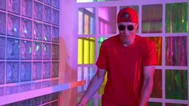 Komik break dansçı kameraya bakarken hiphop 'a doğru serbest adım atıyor. Çılgın mutlu hipster dans edip sokak dansı yaparken Led ışığında günlük kıyafet ve güneş gözlüğü takıyor. Mutluluk.