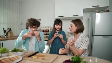 Modern mutfakta oturan ve meyve yiyen mutlu beyaz anne ve babalar. Enerjik aile birlikte vakit geçirerek meyve ya da mutfak gereçleri ve meyveli sağlıklı meyveler yemekten zevk alır. Pedagoji.
