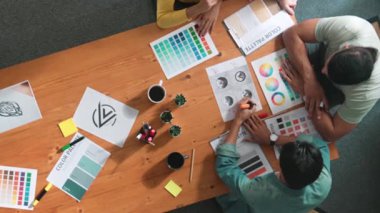 Proje yöneticisi renk paletleri seçerken tasarımcının tablete baktığı yukarıdan aşağıya hava görüntüsü. Profesyonel grafik tasarımının en üst görüntüsü ve logoya bakın. Yetenekli ekip grafikleri seçiyor. Sempozyum.