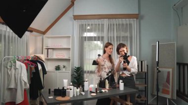 Etkilenen iki ortak canlı yayında video görüntülerini çekiyor makyaj malzemesi prim sosyal medya veya blog. Kozmetik stüdyosu ışıklandırmalı mutlu genç kız çevrimiçi pazarlama oturumu yayını için..