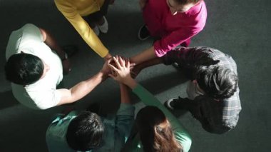 Zeki iş adamlarının birlikte çalışıp el ele tutuşması. Bir grup yetenekli iş adamının beyin fırtınası yapıp toplantı odasında el ele tutuşmalarının havadan görüntüsü. Sempozyum.