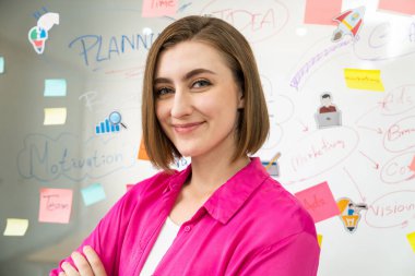 Beyaz tahtanın önündeki kameraya zihin haritası ve renkli yapışkan notlarla bakarken gülümseyen ve kendinden emin bir şekilde poz veren genç beyaz iş kadınının portresi. - Yakın çekim. Tertemiz..