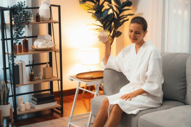 Güzellik ya da vücut bakımı güzellik salonu yaşam tarzı konsepti. Bornoz giyen bir kadın lüks otel kaplıcalarında ya da tatil odasında içkiyle rahatlıyor. Tatil ve boş zaman rahatlığı. Sessiz.